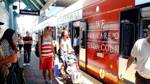Commuters boarding NJ Transit train with CarePoint advertisement