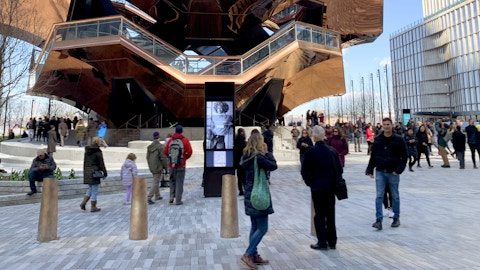 Visitors pass by kiosk with advertising at Hudson Yards