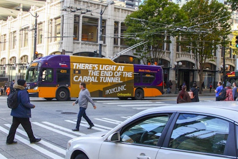 Pedestrians walk by USK bus ad for the Polyclinic