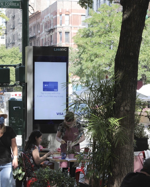 LinkNYC kiosk on NYC street near people dining outside