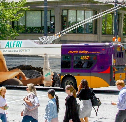 outdoor transit mockup ad in city with people walking by seeing out of home advertising on bus