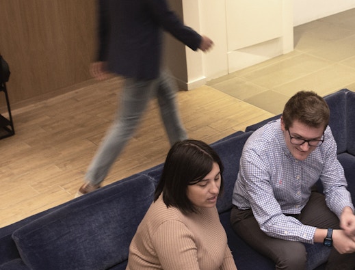 Intersection employees in an office, woman and man on blue couch. Out of home media company, Intersection.