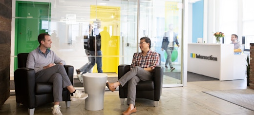 Intersection, out of home media company office on Park Avenue in New York City. 2 employees talking in a busy office