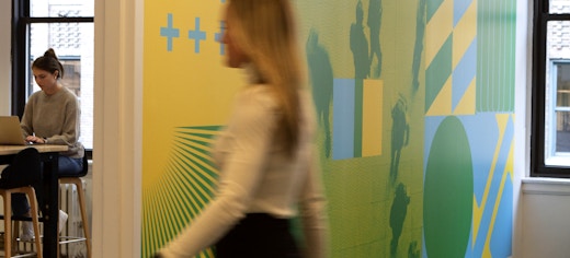 Intersection, Out of Home Media Company in NYC office with woman walking in hallway and woman working on computer